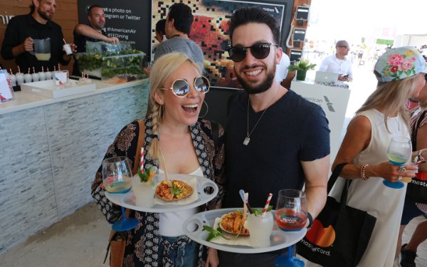 Couple holding food and drink samples at SOBEWFF