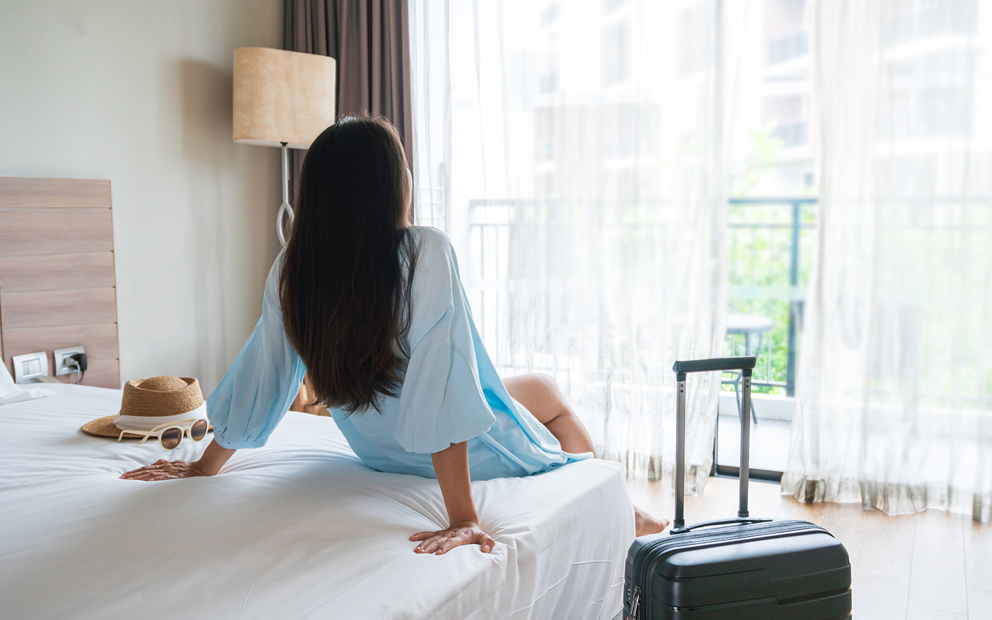 iStock_1436667024_hotel_room_woman_on_bed_1440x900.jpg