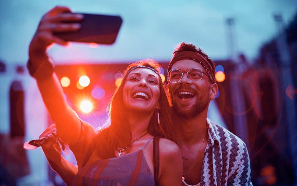 A couple poses for a selfie at a live music concert