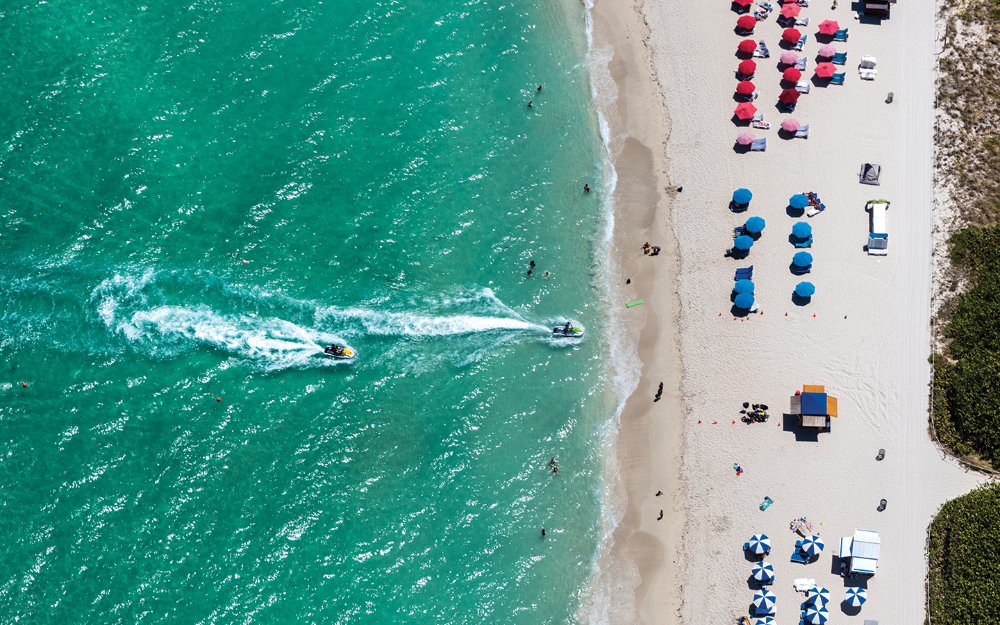 Miami’s turquoise waters jet ski's pulling up to the beach area