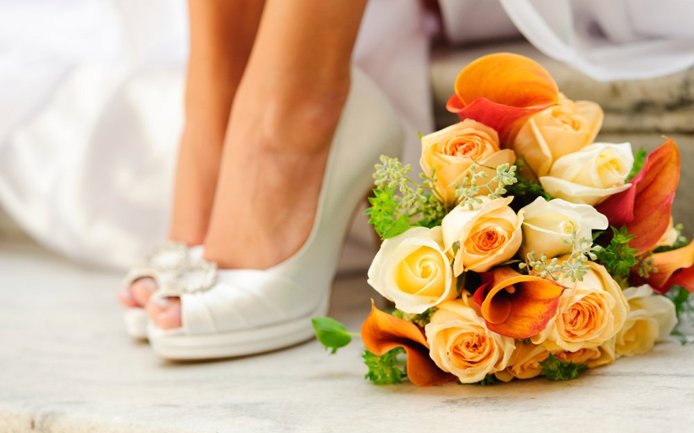 Elegant wedding shoes and a beautiful bridal bouquet with roses and baby breaths decor