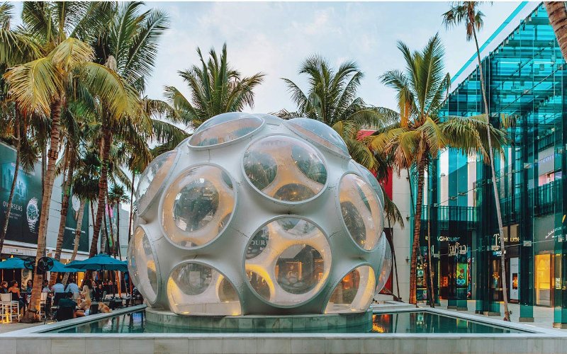 Fly's Eye Dome in Miami's Design District, a striking geometric structure with circular openings, standing out against a bright, modern backdrop