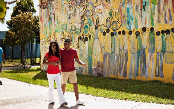 Couple walking by Purvis Young mural in Overtown