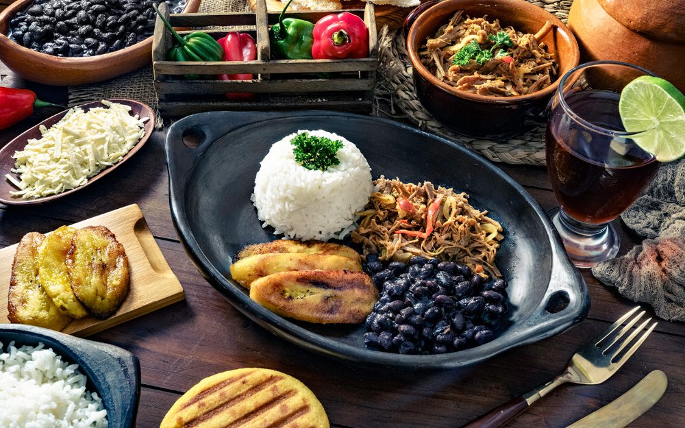 Table of food showing lots of latin food and side dished such as shredded beef, rice and beans, Plaintains